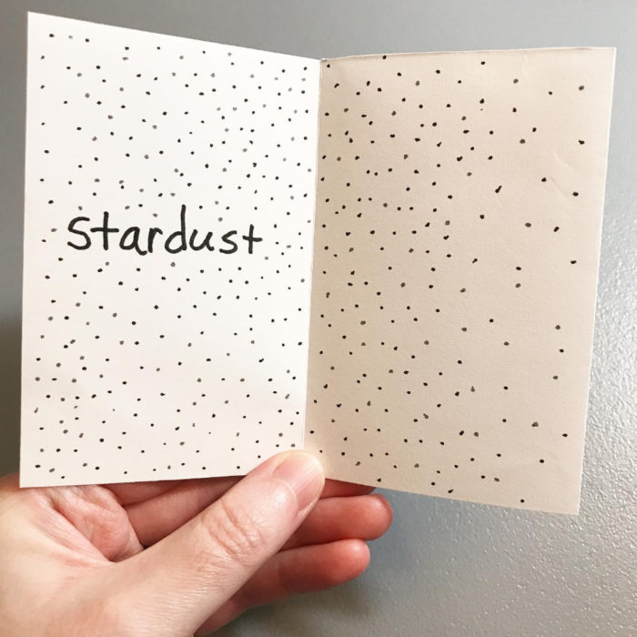 Two-page spread with the word "stardust" and black dots on a white background to signify stars