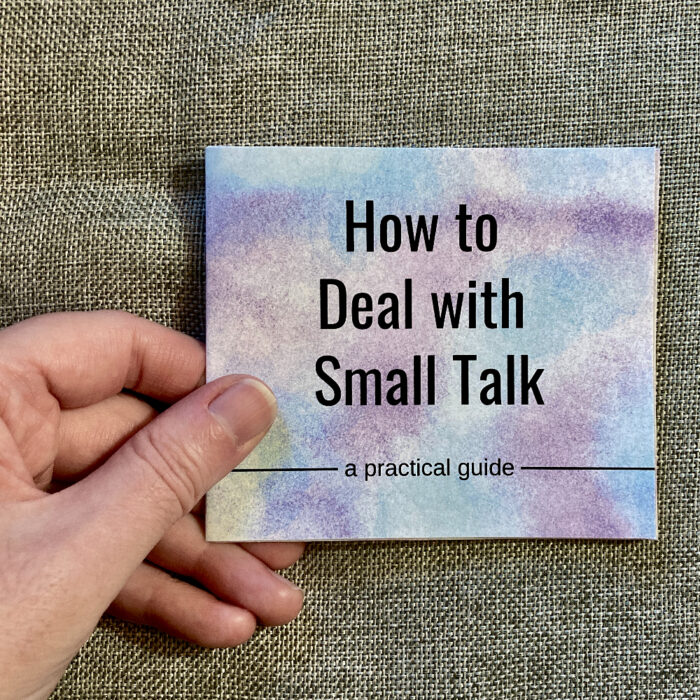 A hand holding the "How to Deal with Small Talk" zine.