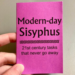 A hand holding the zine "Modern-day Sisyphus." This zine is printed in black on purple paper.